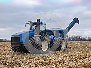 Large tractor pulling a grain cart in a harvested corn field