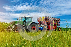 Large tractor on summer field. Low angle view through grass to tractor. Agricultural landscape