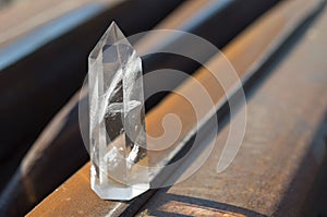 Large transparent mystical faceted crystal of white quartz on a rails on industrial background close-up. A wonderful mineral