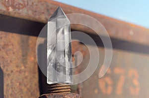 Large transparent mystical faceted crystal of white quartz on a rails on industrial background close-up. A wonderful mineral
