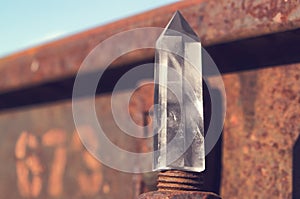 Large transparent mystical faceted crystal of white quartz on a rails on industrial background close-up. A wonderful mineral