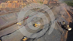 A large truck carries iron ore in the back of a quarry aerial view.