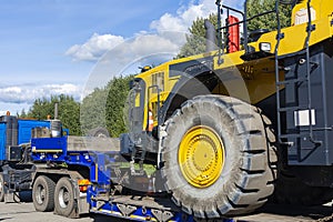 Large truck with a low platform trailer carrying a tractor. A truck for transporting heavy equipment loaded with a large tractor.