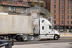 A large truck with a semitrailer in city traffic. A city on the east coast of the USA