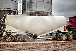 Large truck for transporting cement. A cement truck unloads cement at a concrete plant. Concrete production