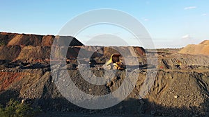 A large truck unloads iron ore in a quarry aerial view.