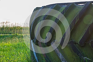 Large truck wheel tire on the grass under grey sky