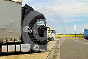 Large trucks of black and white are parked near the road.Delivering or Supply concept. Road train