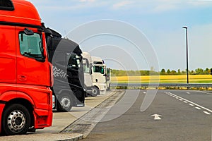 Large trucks of red, black and white are parked near the road.Delivering or Supply concept. Road train