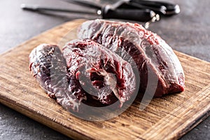 Large uncut pieces of raw beef shank on a chopping board with knives in the background