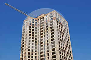 Large unfinished gray brown house with windows and a tower crane