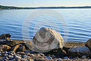 A large upright rock rock sits, like an egg, on the beach