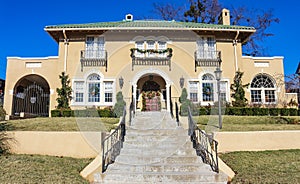 Large upscale adobe home with steps leading up to it decorated for Christmas