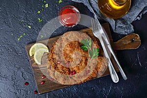 Large Viennese schnitzel on a black background. Meat dish.