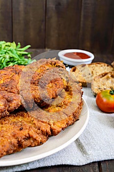 A large Viennese schnitzel on a dark wooden background.