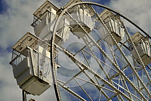 Large vintage style ferris wheel against a sky with broken clouds