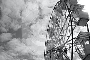 Large vintage style ferris wheel against a sky with broken clouds