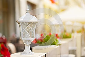 Large vintage white street lamp standing on the porch.