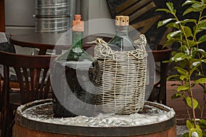 Large Vintage Wine Bottles in wicker basket on a barrel