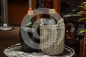 Large Vintage Wine Bottles in wicker basket on a barrel