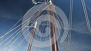 A large vintage wooden yacht sails on the sea. View of the bow of the yacht with furled sails.