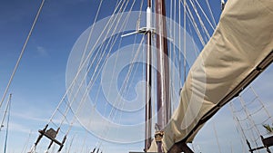 A large vintage wooden yacht sails on the sea. View of the bow of the yacht with furled sails.