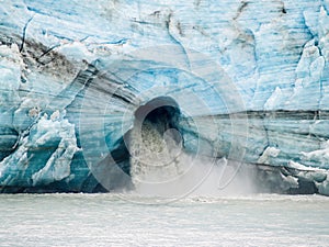 Large volume of melt water gushes from large hole in the face of