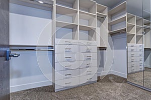 Large walk-in closet with white shelves, drawers