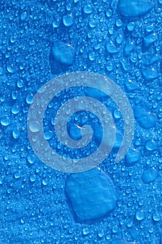 Large water droplets on blue polyethylene blue tarpaulin in daylight Vertical