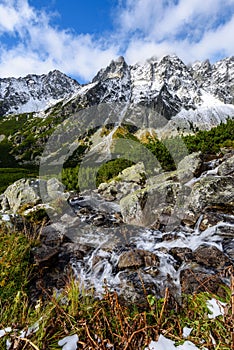 Large Waterfall from ravine in autumn, long exposure with mountains in background