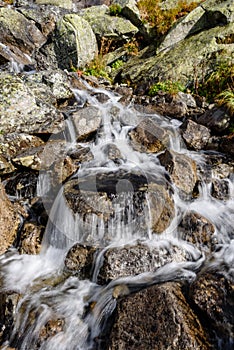 Large Waterfall from ravine in autumn, long exposure with mountains in background