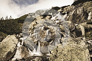 Velký vodopád z rokle na podzim, dlouhá expozice s horami v pozadí - vzhled vintage filmu