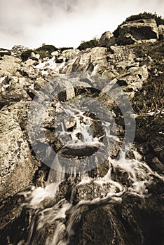 Large Waterfall from ravine in autumn, long exposure with mountains in background - vintage film look