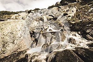 Large Waterfall from ravine in autumn, long exposure with mountains in background - vintage film look