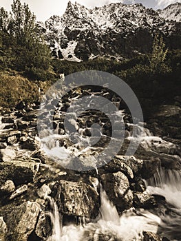 Large Waterfall from ravine in autumn, long exposure with mountains in background - vintage film look