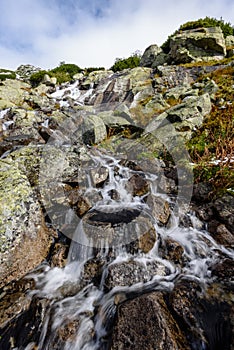 Large Waterfall from ravine in autumn, long exposure with mountains in background