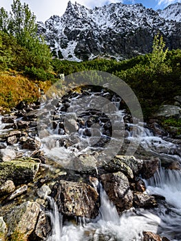 Velký vodopád z rokle na podzim, dlouhá expozice s horami v pozadí
