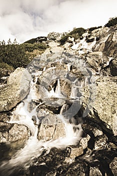 Velký vodopád z rokle na podzim, dlouhá expozice s horami v pozadí - vzhled vintage filmu