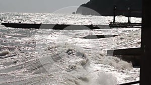 A large wave breaks about a breakwater close-up against a sunset background. Shot. Seascape. Sea water storm waves