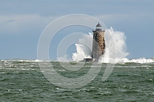 Large Wave Covers Stone Lighthouse Tower in Maine