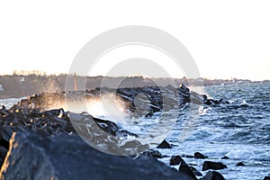 Large wave hitting rock at sunset