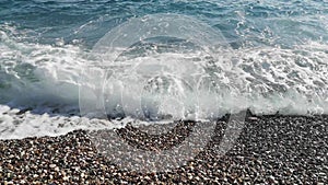 A large wave is throws ashore and washed colorful pebbles - top view - 23s