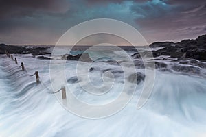 Large wave volume of water flowing fast into rock pool