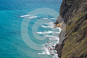 Large waves crash on the rocky shore view from above.