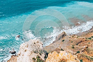 Large waves crash on the rocky shore view from above.