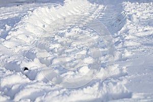 Large wheel trail with deep tread in the snow, close-up, selective focus