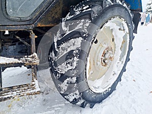 large wheels of a blue tractor in a snowy forest.