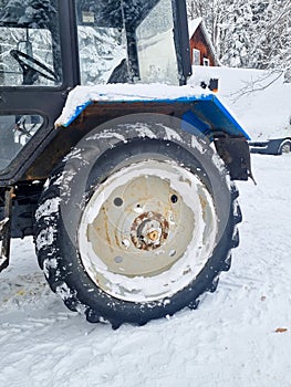 large wheels of a blue tractor in a snowy forest.