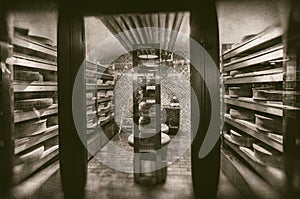 Large wheels of cheese maturing in storehouse dairy cellar - retro photography