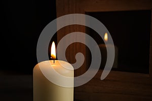 Large white candle burning in the darkness with reflection